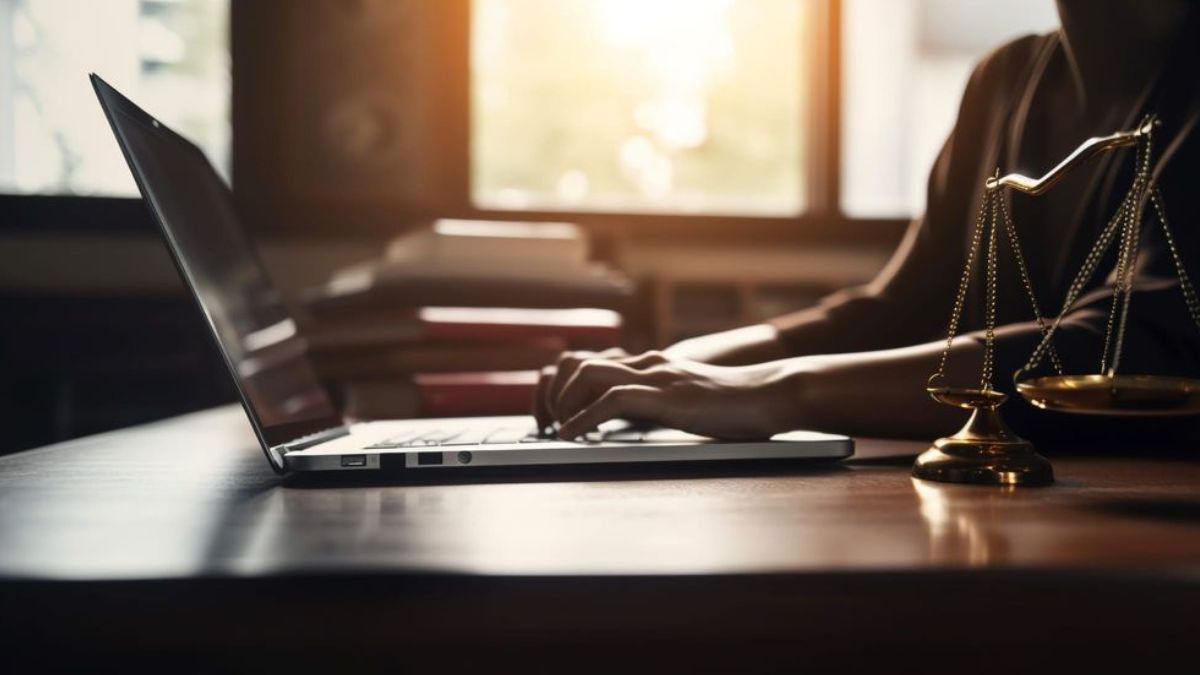 Balança da justiça ao lado de um notebook para ilustrar o risco regulatório do trabalho híbrido