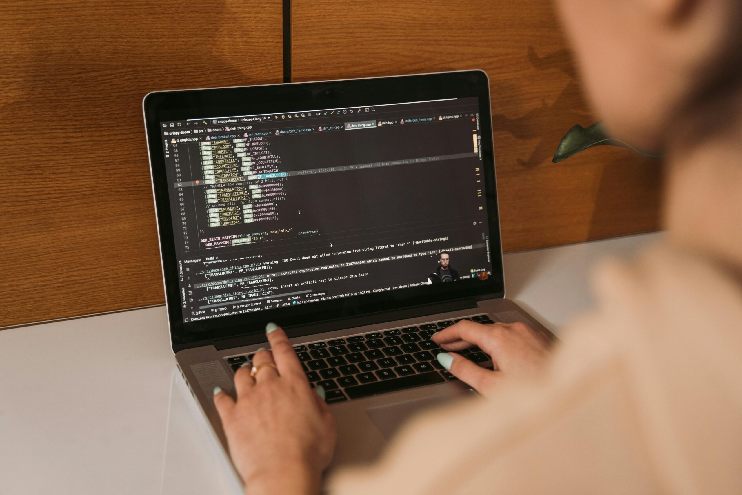 Mãos de uma pessoa digitando em um notebook com linhas de código de programação