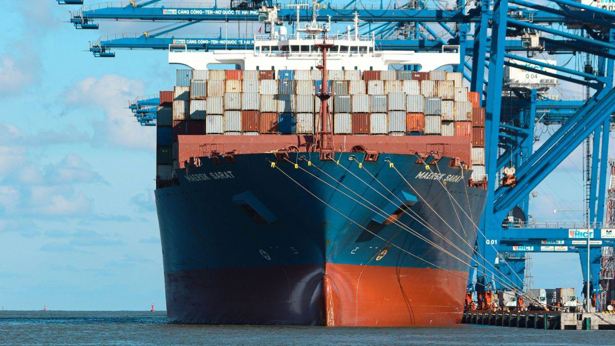 Navio cargueiro carregando contêineres em um porto para ilustrar os impactos das novas barreiras comerciais na economia