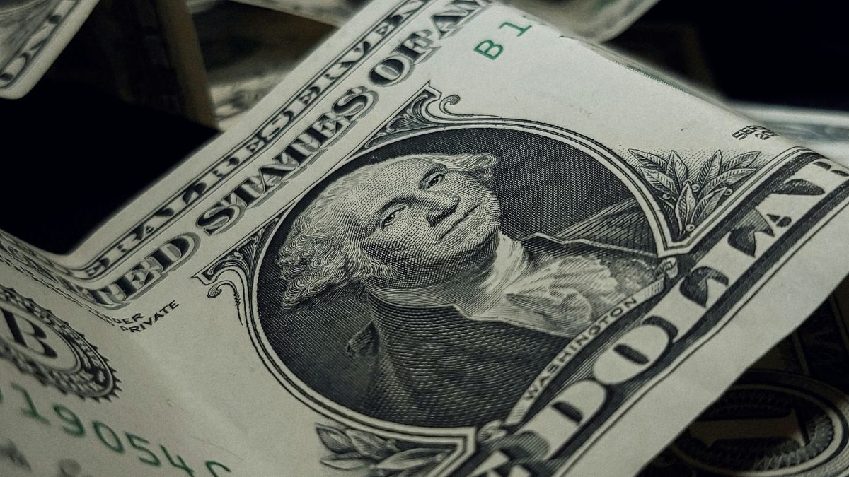 Nota de dólar simbolizando a cotação do dólar hoje em movimento de queda no mercado cambial