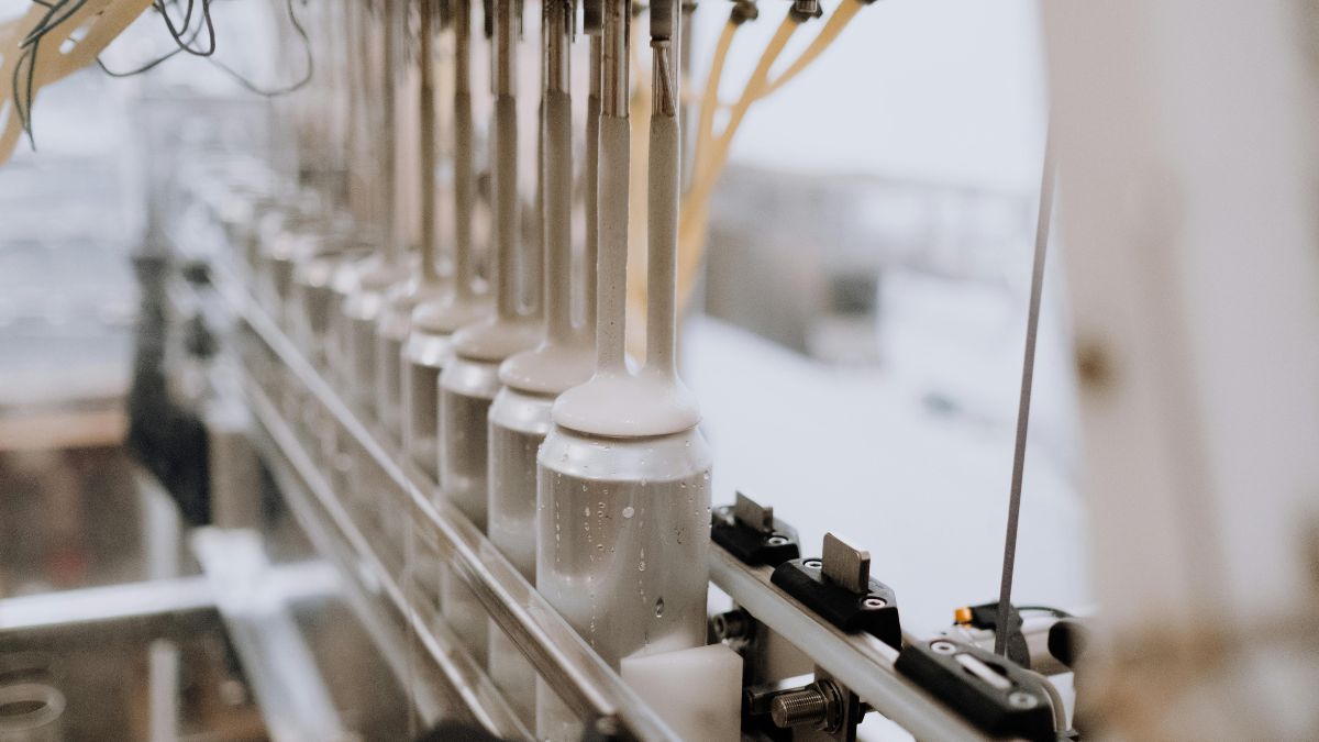 Linha de produção industrial com braços mecânicos enchendo latas de alumínio, representando os setores beneficiados pelo crédito empresarial no país