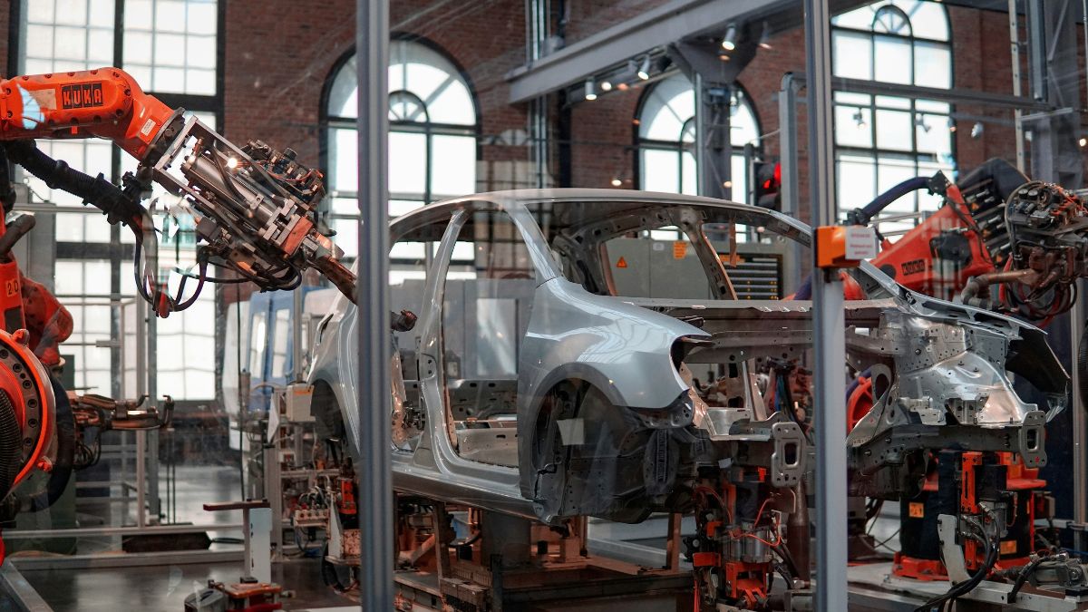 Montadora de carros com braço mecânico operando na montagem, simbolizando a mudança no imposto de importação de carros elétricos