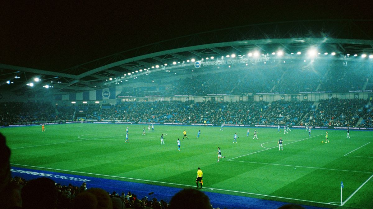 Estádio de futebol à noite, simbolizando o investimento no mercado de futebol