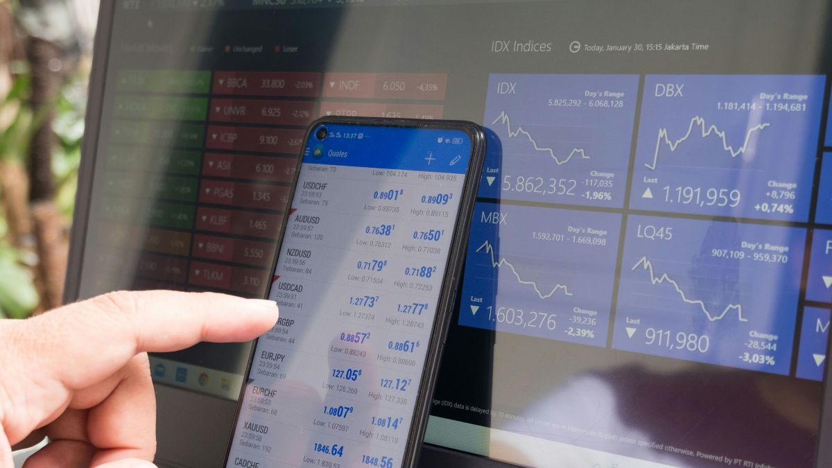Tela de laptop e celular mostrando gráficos financeiros, para indicar a reação do mercado à ata da Copom
