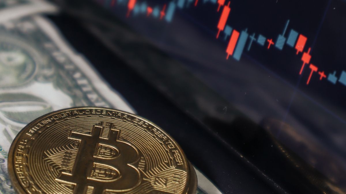 Bitcoins sobre dólares em frente a um gráfico financeiro, simbolizando o risco do bitcoin apontado pelos especialistas em Nova York