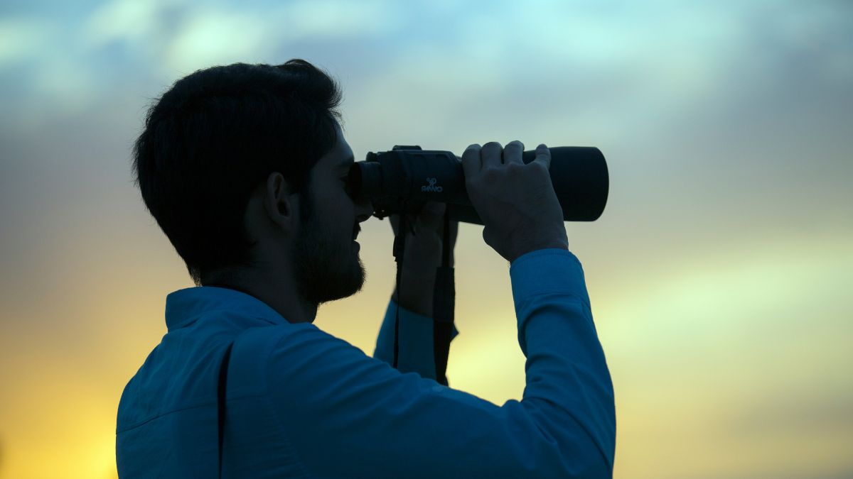 Homem de binóculos avistando o horizonte, simbolizando o planejamento da Shippify ao fugir da guerra fiscal de aplicativos de entrega