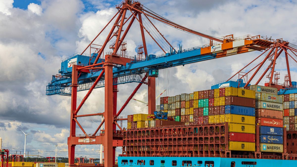 Guindastes industriais movimentando contêineres em um porto de carga, ilustrando o superávit da balança comercial brasileira