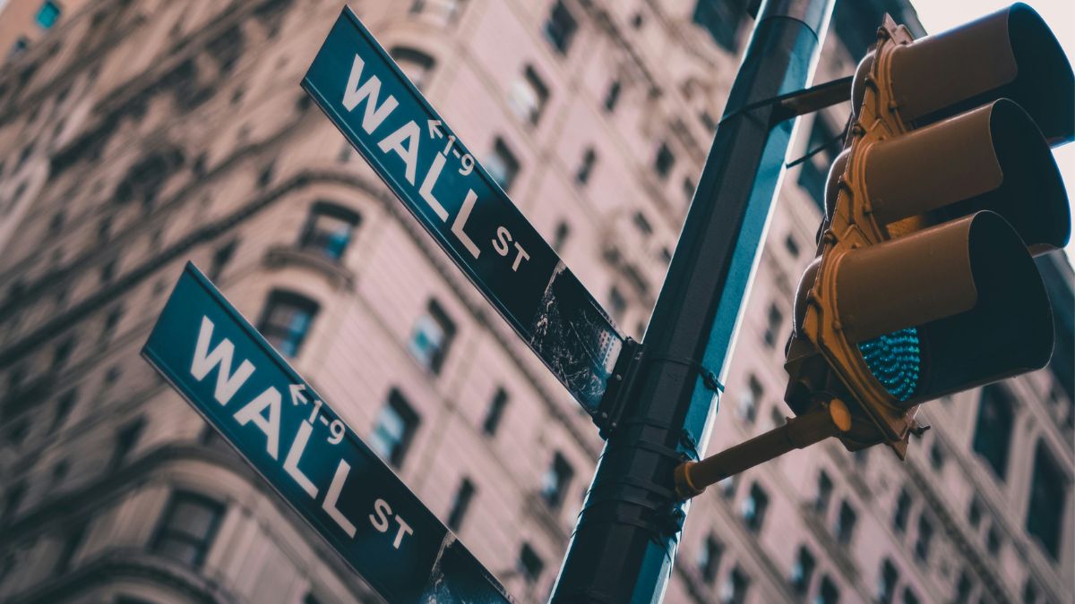 Placas de trânsito tradicionais com a indicação "WALL ST" em destaque, simbolizando o aumento das compras estrangeiras no S&P 500 por causa da IA