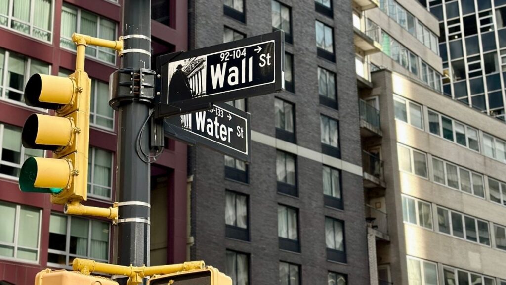 Detalhe da arquitetura de Wall Street, com placa de rua e semáforo para simbolizar a decisão do FOMC e os impactos no mercado