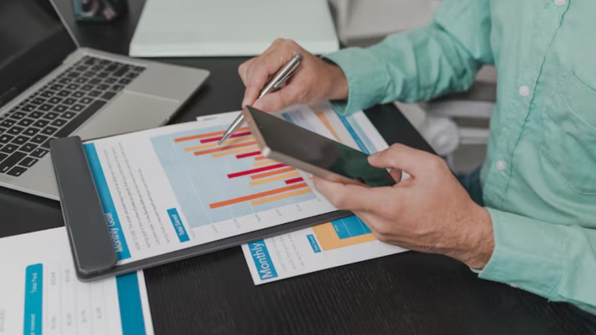 Mesa com gráficos financeiros sendo analisados, para simbolizar que a inadimplência das empresas brasileiras atingiu recorde