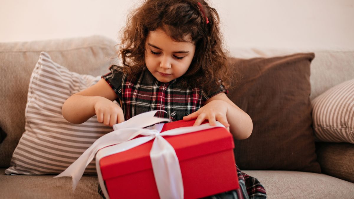 Menina abrindo um presente, simbolizando que o Dia das Crianças de 2026 tem boas expectativas para o varejo, com projeção de movimentar R$ 9,27 Bi