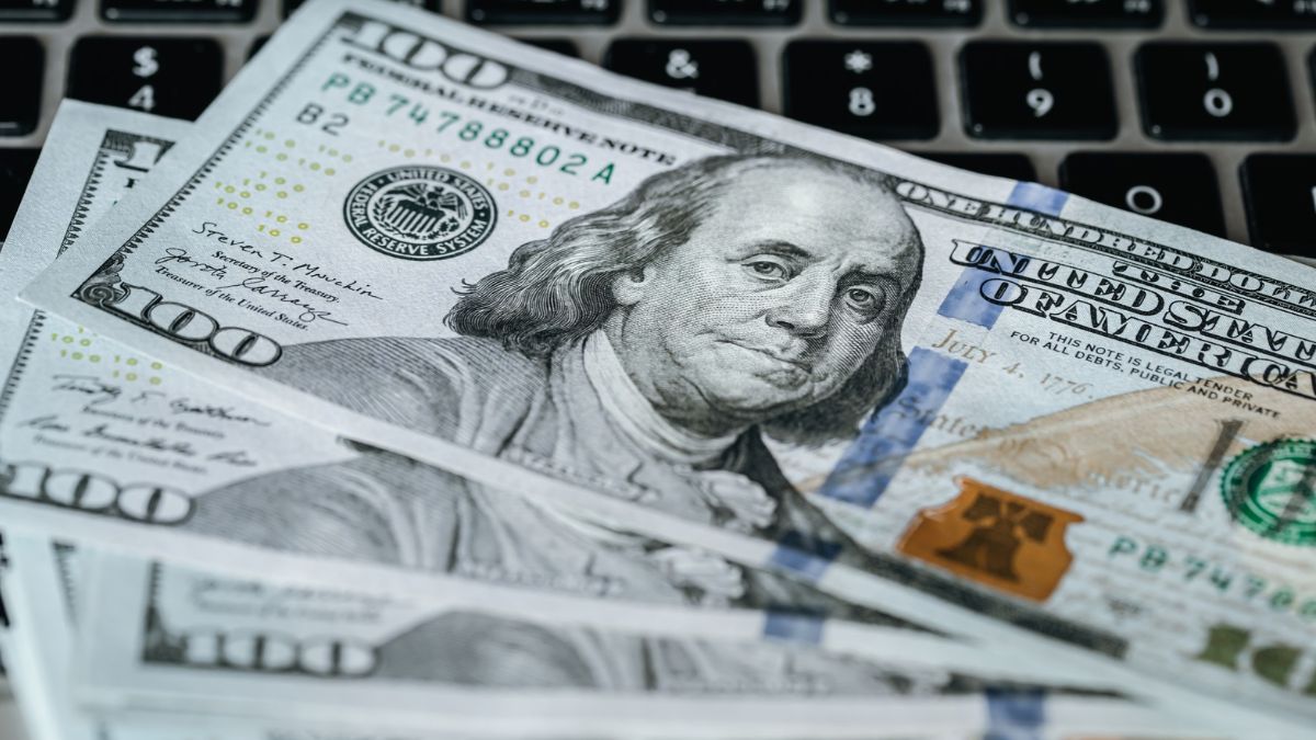 Notas de dólar sobre o teclado do computador, para simbolizar que o mercado reage a pesquisas eleitorais com alta do dólar no Brasil