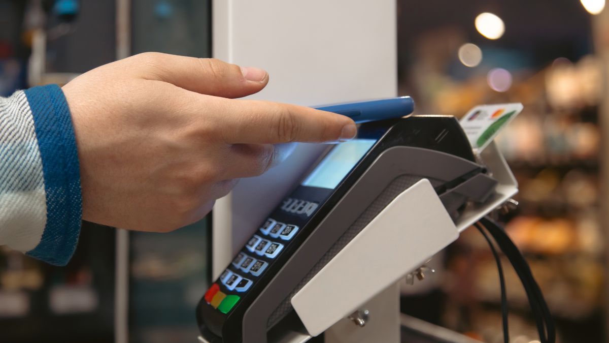 Maquininha de vendas com celular fazendo a compra por aproximação, simbolizando que o split payment acende alerta para o capital de giro das empresas, ocasionando debates econômicos e políticos