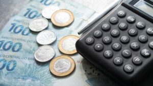 Notas de Real, moedas e calculadora, simbolizando que o TCU fixou alíquota da CBS para 2027